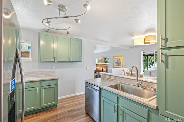 kitchen featuring a sink, appliances with stainless steel finishes, a textured ceiling, and green cabinets