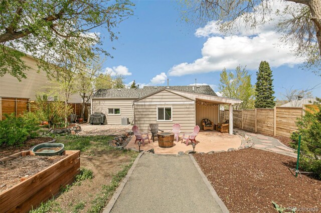 rear view of house featuring a patio, a fire pit, a garden, and a fenced backyard