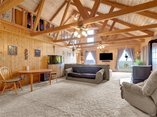 carpeted living room featuring beam ceiling, ceiling fan, high vaulted ceiling, wood walls, and wood ceiling