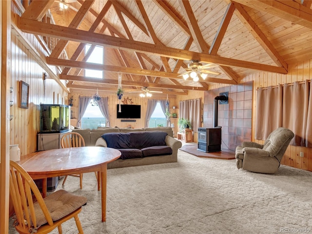 carpeted living room featuring a wood stove, a wealth of natural light, beamed ceiling, and wooden ceiling