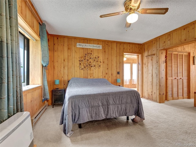 bedroom featuring ceiling fan, light carpet, a textured ceiling, and a baseboard heating unit