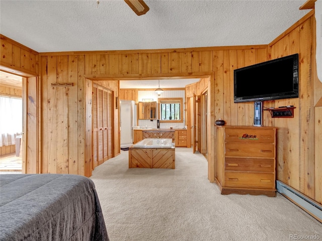 carpeted bedroom with ceiling fan, sink, wooden walls, and a baseboard radiator