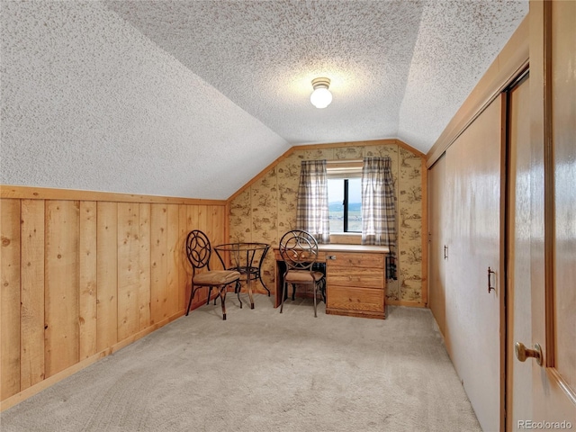 carpeted home office with lofted ceiling and a textured ceiling