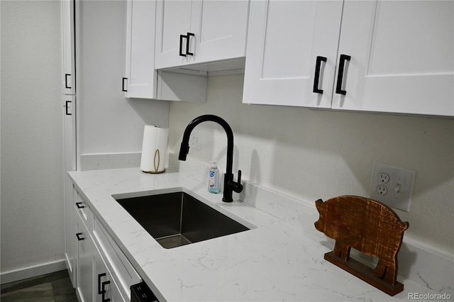 kitchen featuring sink, white cabinets, and light stone counters