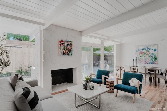 living room featuring a fireplace, beam ceiling, and light wood-type flooring