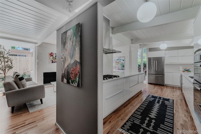 kitchen with white cabinetry, appliances with stainless steel finishes, light hardwood / wood-style floors, and beam ceiling