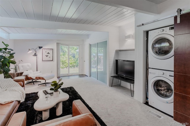 laundry area featuring carpet, a barn door, and stacked washer and dryer