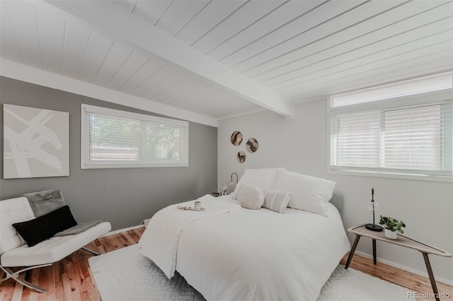 bedroom with beamed ceiling, multiple windows, and hardwood / wood-style floors