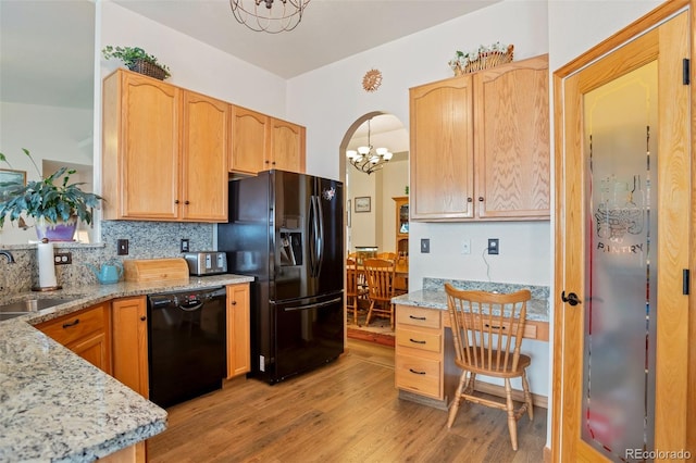 kitchen featuring light stone countertops, light hardwood / wood-style flooring, sink, and black appliances