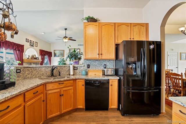 kitchen featuring light stone counters, light hardwood / wood-style floors, tasteful backsplash, sink, and black appliances