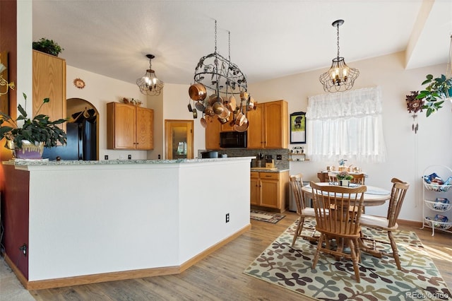 kitchen with black appliances, kitchen peninsula, decorative backsplash, and light hardwood / wood-style flooring