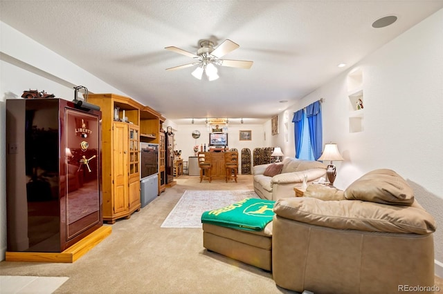 carpeted living room with ceiling fan, bar area, and a textured ceiling