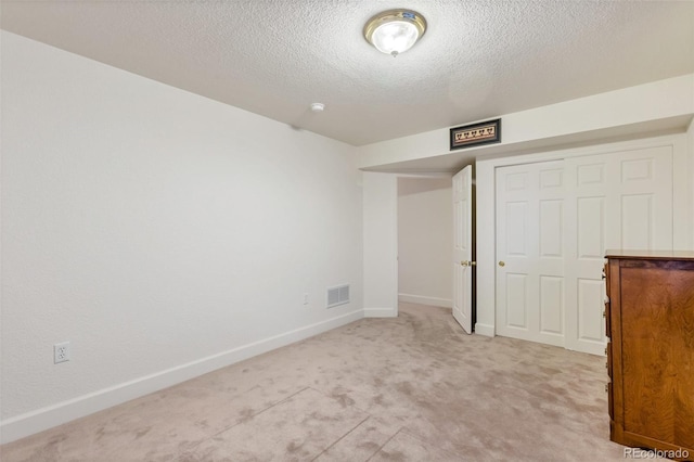 unfurnished bedroom with a closet, light colored carpet, and a textured ceiling