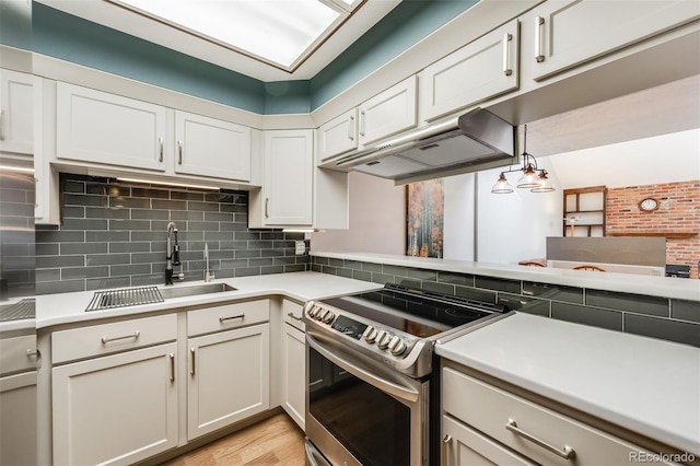 kitchen with under cabinet range hood, backsplash, light countertops, and electric stove