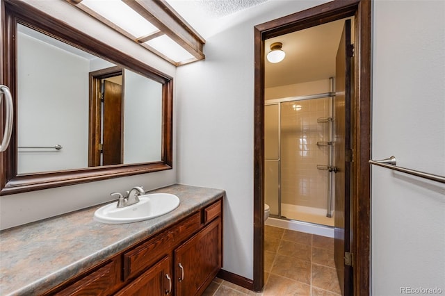 bathroom with a shower stall, toilet, vanity, and baseboards