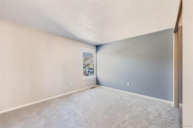 carpeted empty room with baseboards and a textured ceiling