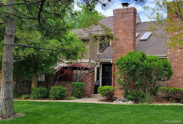 11710 Elk Head Range Rd, Littleton, CO 80127 - view of front of home featuring a chimney, a shingled roof, a front yard, and brick siding