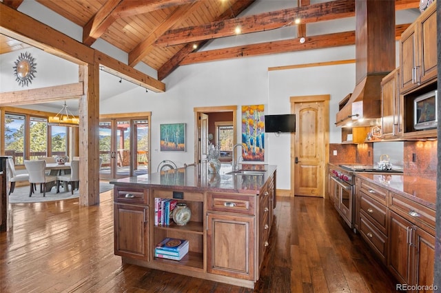 kitchen featuring a center island with sink, appliances with stainless steel finishes, beamed ceiling, french doors, and sink