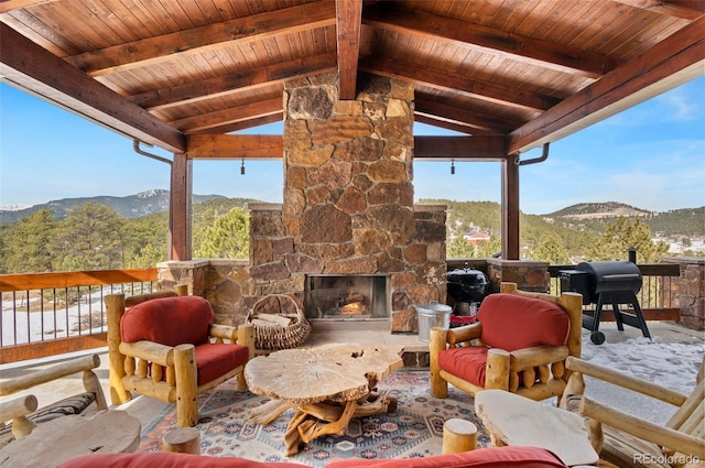 view of patio / terrace featuring a grill, a mountain view, and an outdoor stone fireplace