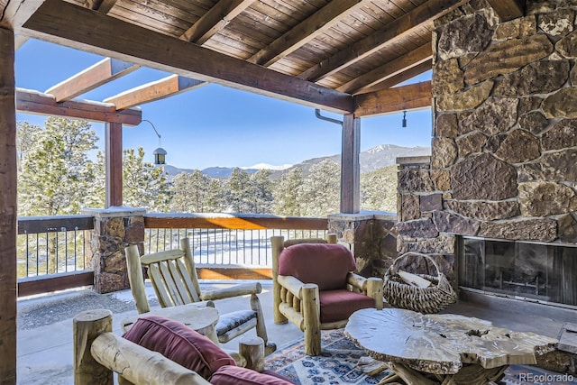 deck featuring an outdoor stone fireplace and a mountain view