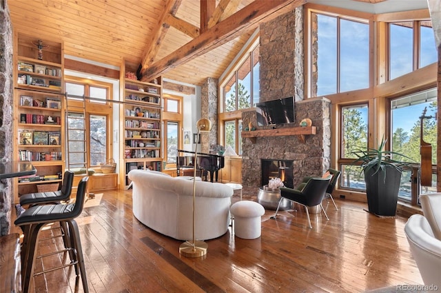 living room with wood ceiling, hardwood / wood-style floors, a stone fireplace, beamed ceiling, and high vaulted ceiling