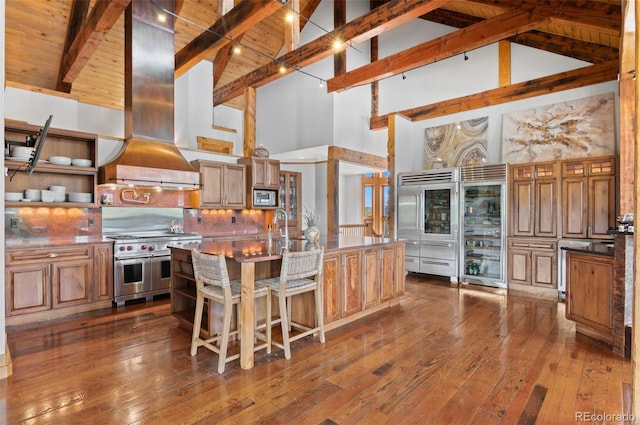 kitchen with built in appliances, island range hood, high vaulted ceiling, beam ceiling, and wine cooler