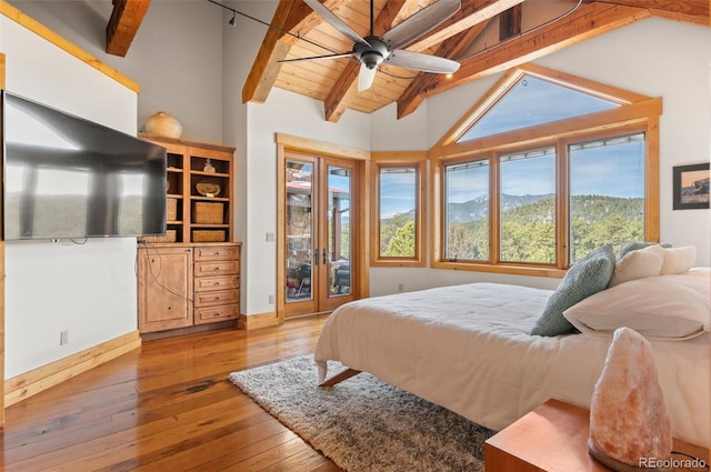 bedroom with light wood-type flooring, vaulted ceiling with beams, ceiling fan, a mountain view, and access to outside