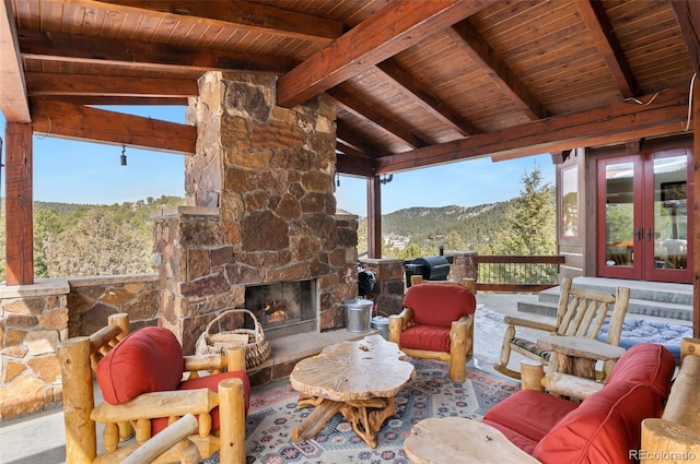 view of patio / terrace featuring a grill, french doors, a mountain view, and an outdoor stone fireplace