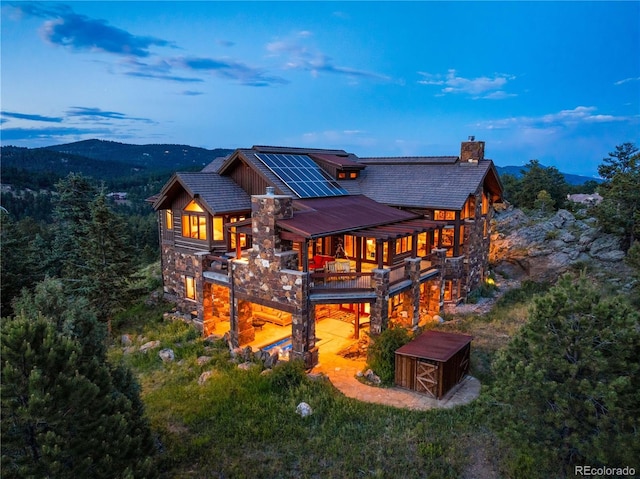 back house at dusk with a mountain view and solar panels