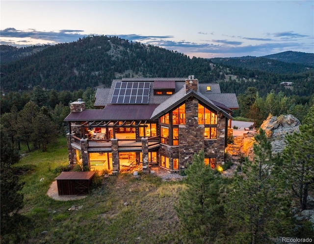 back house at dusk featuring solar panels and a mountain view