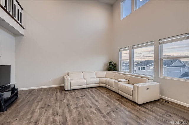 unfurnished living room featuring a towering ceiling and light hardwood / wood-style floors