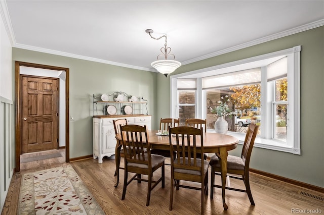 dining area with crown molding, baseboards, visible vents, and light wood-style flooring