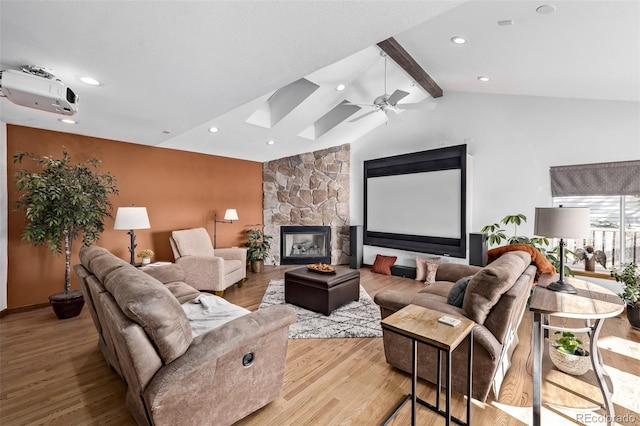 living room with vaulted ceiling with skylight, a fireplace, a ceiling fan, recessed lighting, and wood finished floors