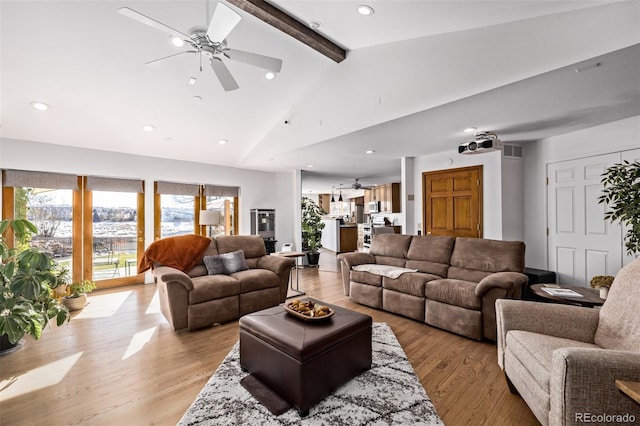 living room featuring a wealth of natural light, ceiling fan, beam ceiling, and visible vents
