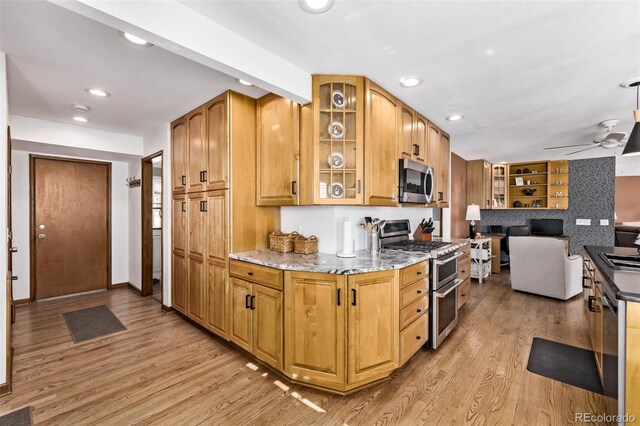 kitchen featuring light stone countertops, appliances with stainless steel finishes, light wood-style flooring, recessed lighting, and glass insert cabinets