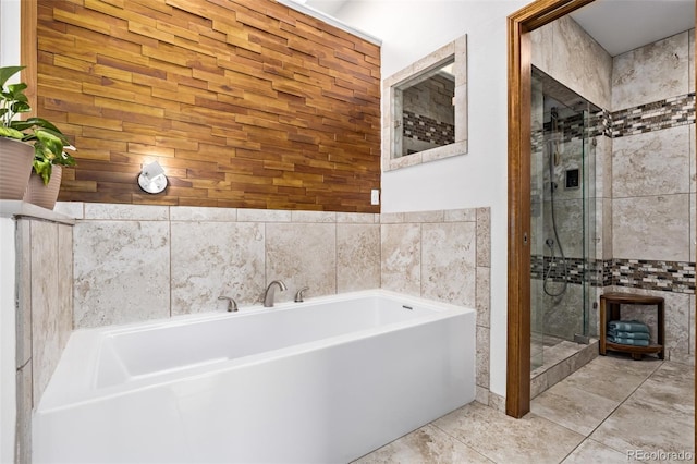 bathroom with a stall shower, a bath, and tile walls