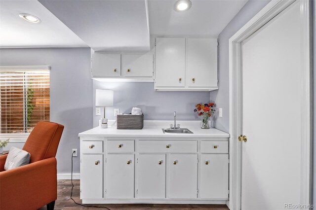 kitchen with wood finished floors, recessed lighting, light countertops, white cabinetry, and a sink