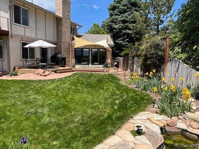 view of yard featuring fence, a sunroom, and a patio area