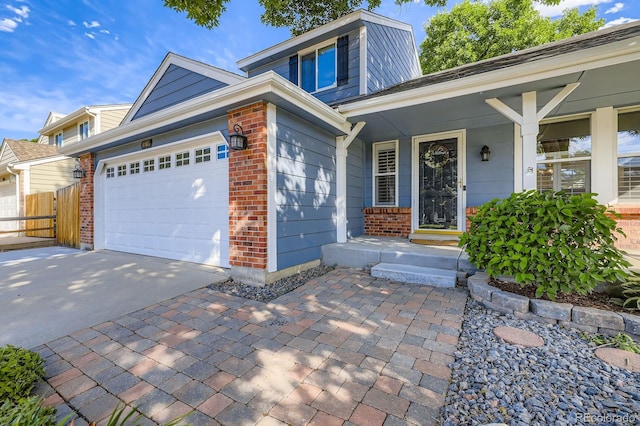 8985 W Quarto Pl, Littleton, CO 80128 - view of front of property with brick siding, a garage, driveway, and a porch