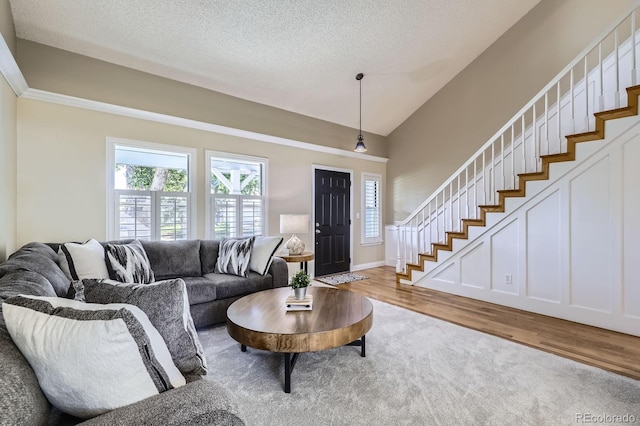 8985 W Quarto Pl, Littleton, CO 80128 - living room featuring stairway, light wood finished floors, lofted ceiling, and a textured ceiling