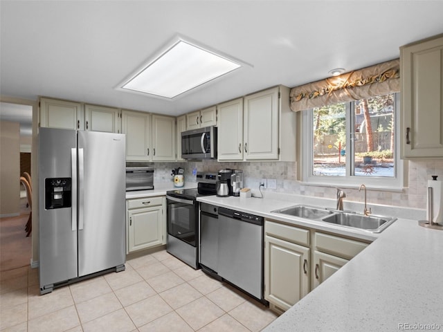 kitchen with tasteful backsplash, sink, light tile patterned flooring, and stainless steel appliances