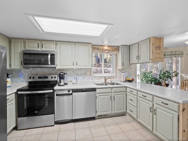 kitchen featuring kitchen peninsula, sink, light tile patterned flooring, and appliances with stainless steel finishes