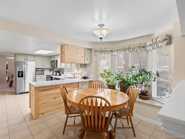 tiled dining room with a skylight and sink