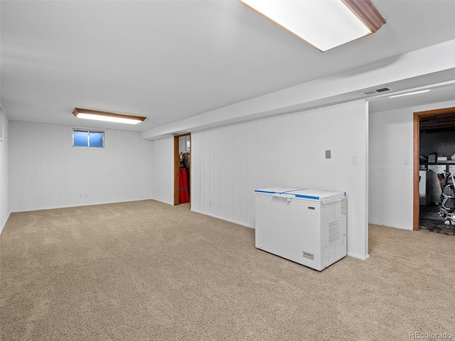 basement with light colored carpet, wooden walls, and fridge