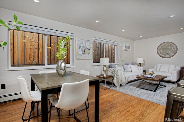 dining room featuring an AC wall unit, a baseboard heating unit, and light hardwood / wood-style floors