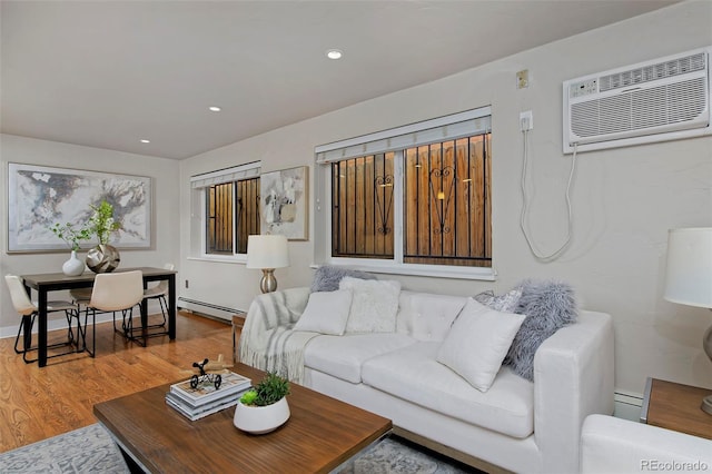 living room featuring a baseboard heating unit, wood-type flooring, and a wall mounted AC