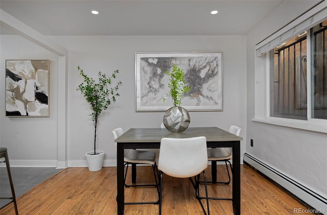 dining area featuring a baseboard heating unit and hardwood / wood-style floors