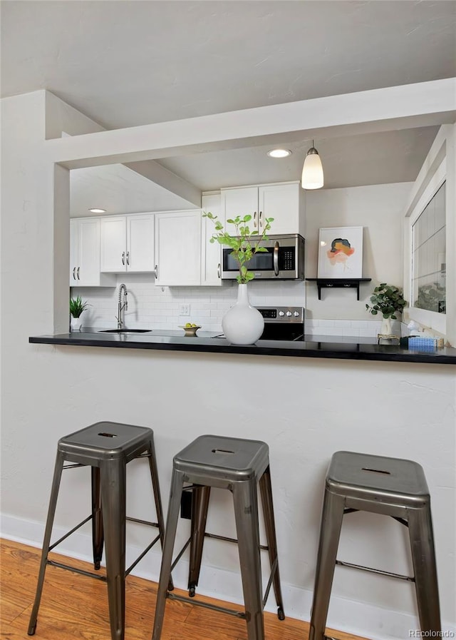 kitchen featuring sink, white cabinetry, tasteful backsplash, hanging light fixtures, and appliances with stainless steel finishes