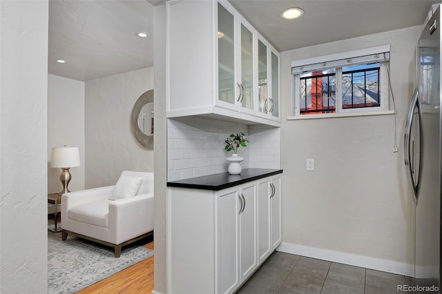 kitchen featuring backsplash, white cabinets, stainless steel refrigerator, and dark tile patterned flooring