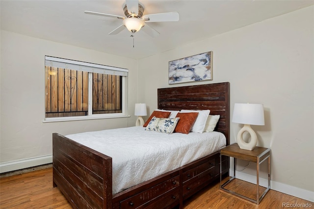 bedroom featuring a baseboard heating unit, light hardwood / wood-style flooring, and ceiling fan